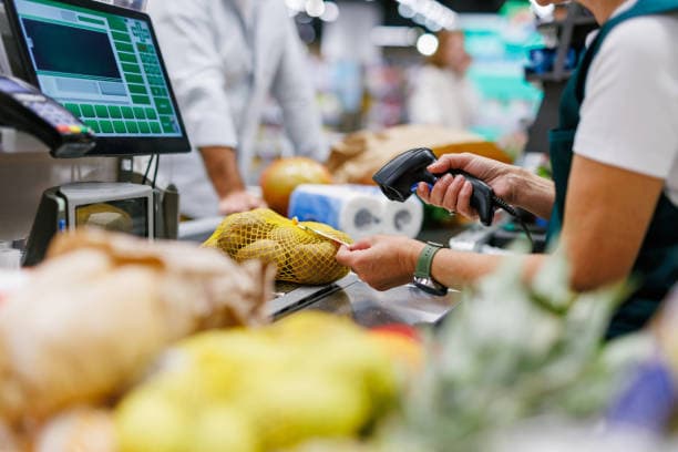 Cashier scanning items at a busy convenience shop counter
