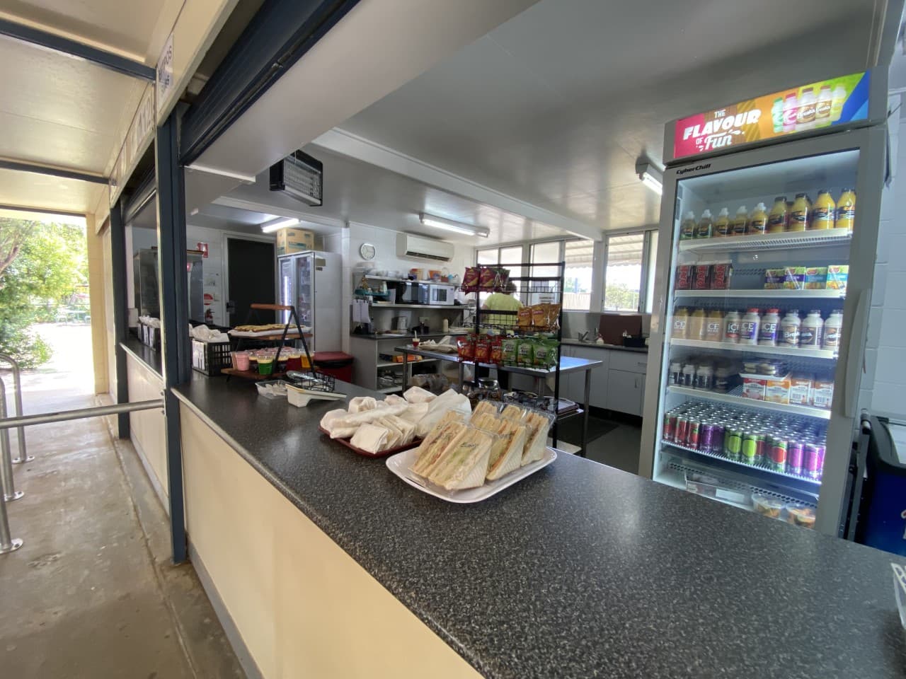 School canteen counter with sandwiches, snacks and a chilled drinks fridge
